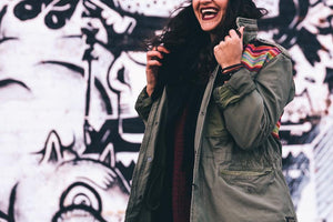 woman wearing olive green jacket in front of graffiti 